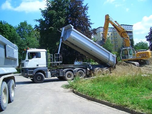 Kipper von Hartl beim Abkippen, dahinter ein Bagger